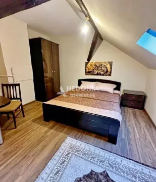 Nameštena spavaća soba sa bračnim krevetom i drvenim gredama na plafonu. - image 3