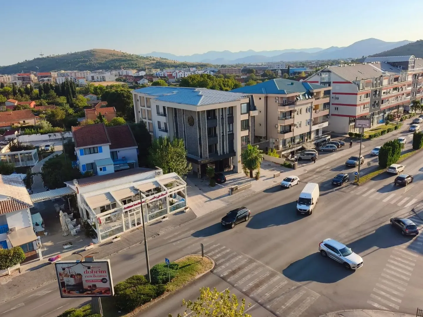 Pogled iz zgrade na okolne ulice, gradsku zonu i planine u pozadini.