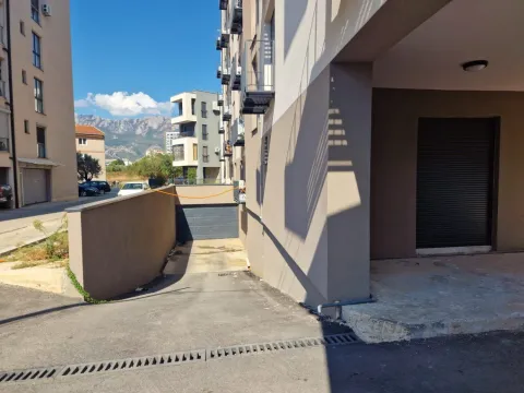 Eksterijer zgrade sa ulazom u garažu i okolnim objektima. - image 4