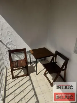 Manji sto i dve drvene stolice na popločanoj terasi. - image 9