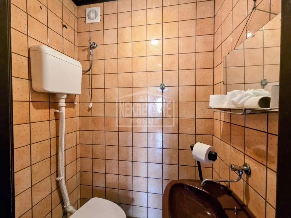 Manje kupatilo obloženo keramičkim pločicama u braon tonovima sa umivaonikom i wc šoljom.