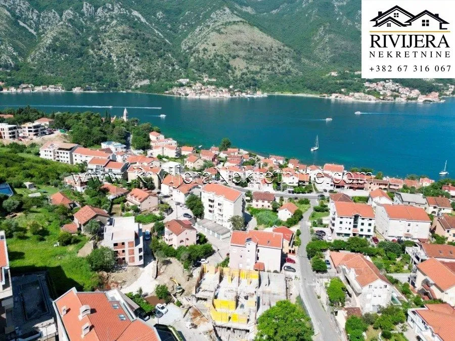 Pogled iz vazduha na obalu mora i naselje sa planinama u pozadini.