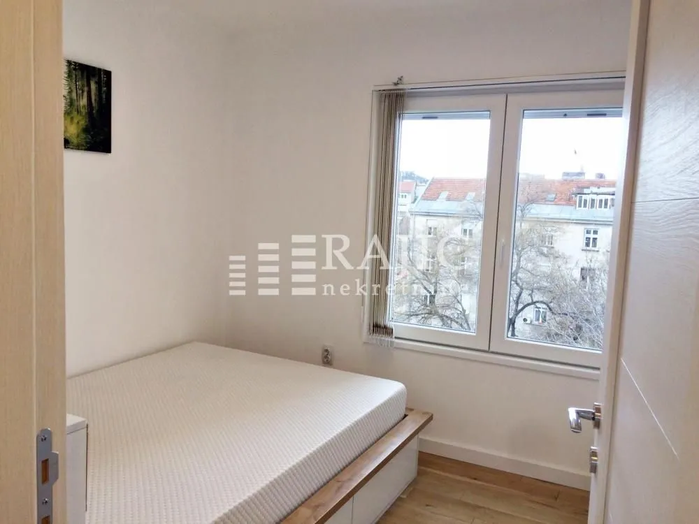 Smaller bedroom with a bed and a window overlooking the city.