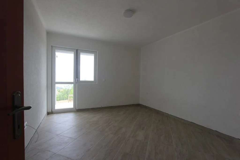 An empty room with light floor tiles and a balcony door.