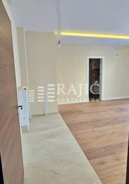 Unutrašnjost prazne prostorije sa drvenim podom i vodenim žigom agencije. - image 9