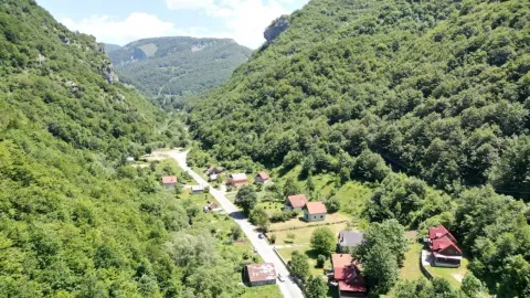 Pogled iz vazduha na seosko naselje okruženo šumom i planinama. - image 4