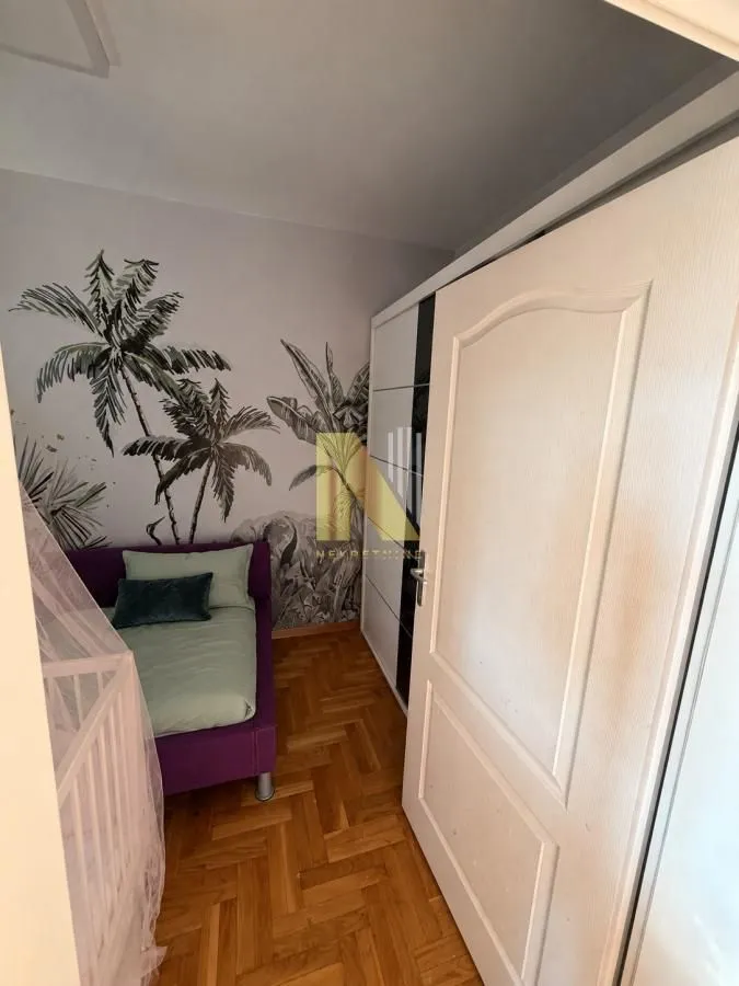Dečja soba sa krevetom, garderoberom i tapetama sa motivom džungle.