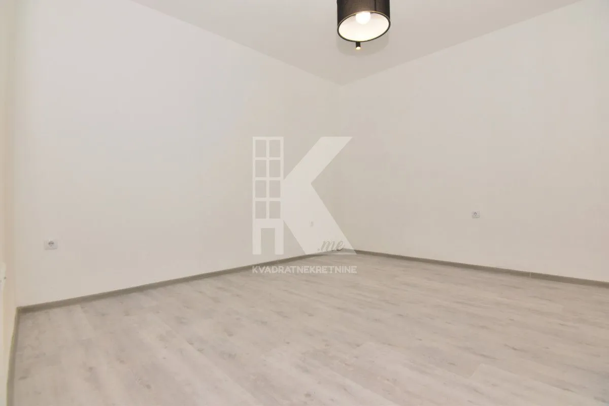 Empty room with white walls, light laminate flooring, and a ceiling light fixture.