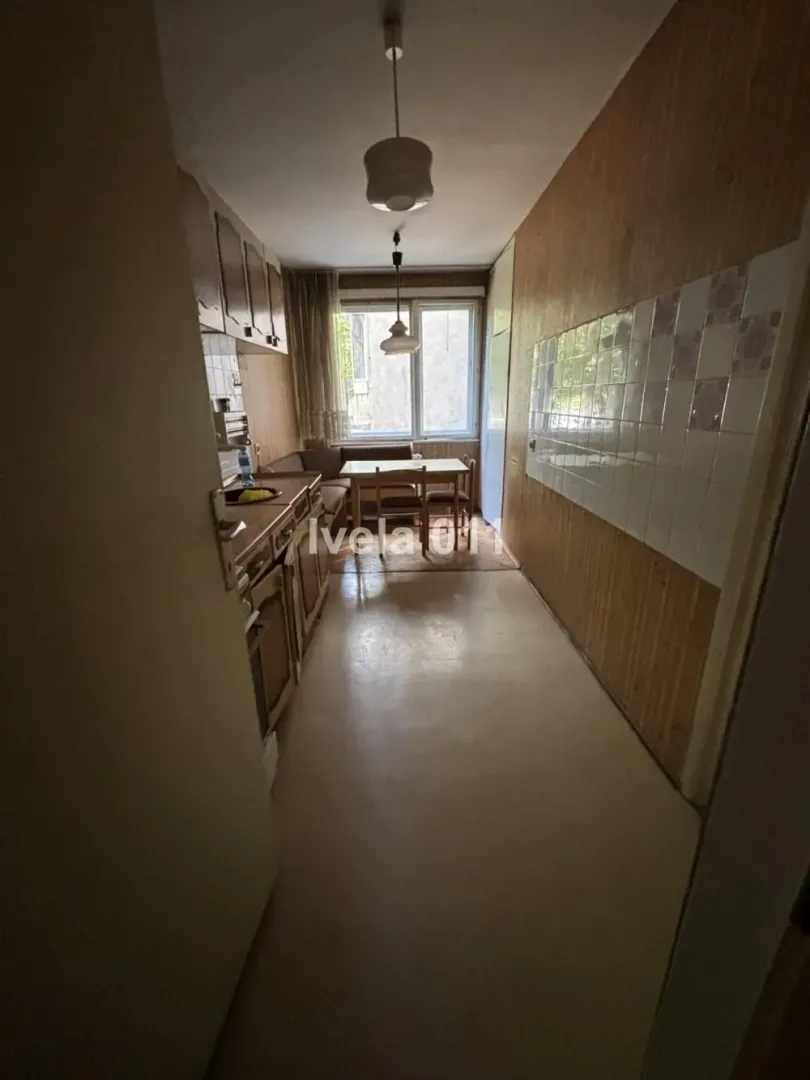 Manja kuhinja sa trpezarijskim stolom i prozorom na kraju prostorije.