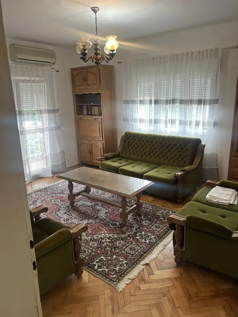 Living room with classic green furniture and wooden parquet.