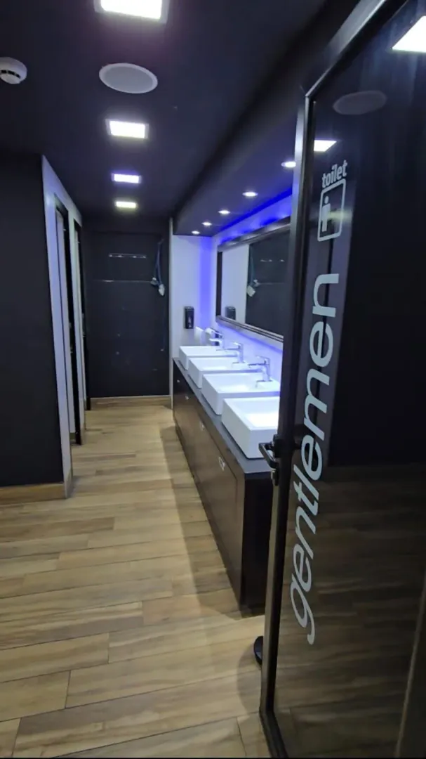 Modern public restrooms with washbasins and wooden flooring.