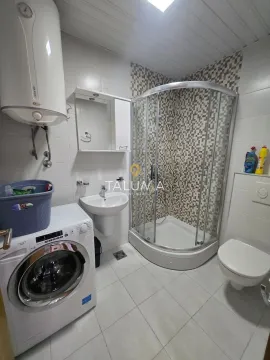 Bathroom equipped with a shower cabin, washbasin, toilet, and washing machine. - image 8
