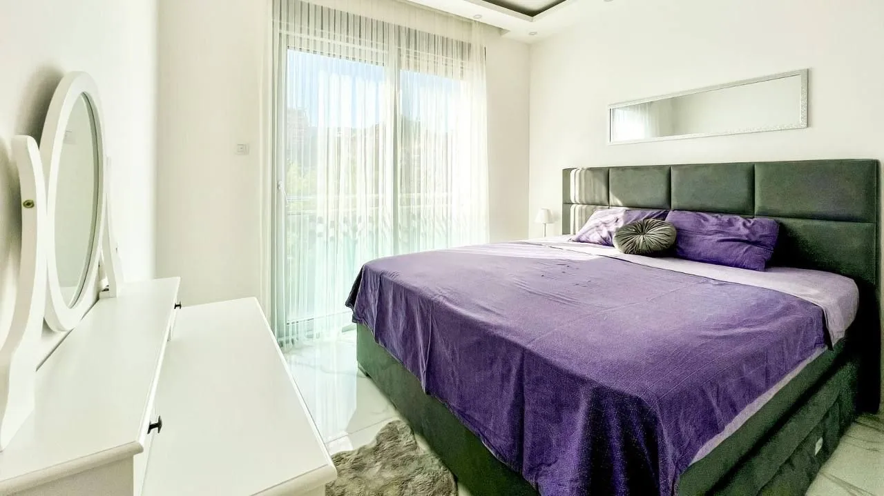 Spacious bedroom with a large double bed, white furniture, and access to the terrace.