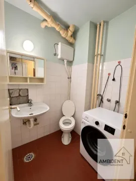 Small bathroom with a washbasin, toilet, and washing machine. - image 5