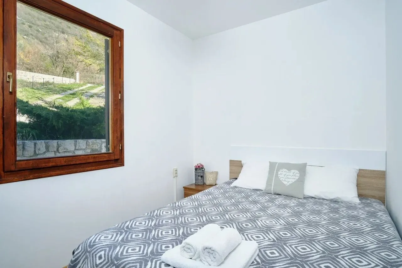 Bright bedroom with a double bed and a window overlooking nature.