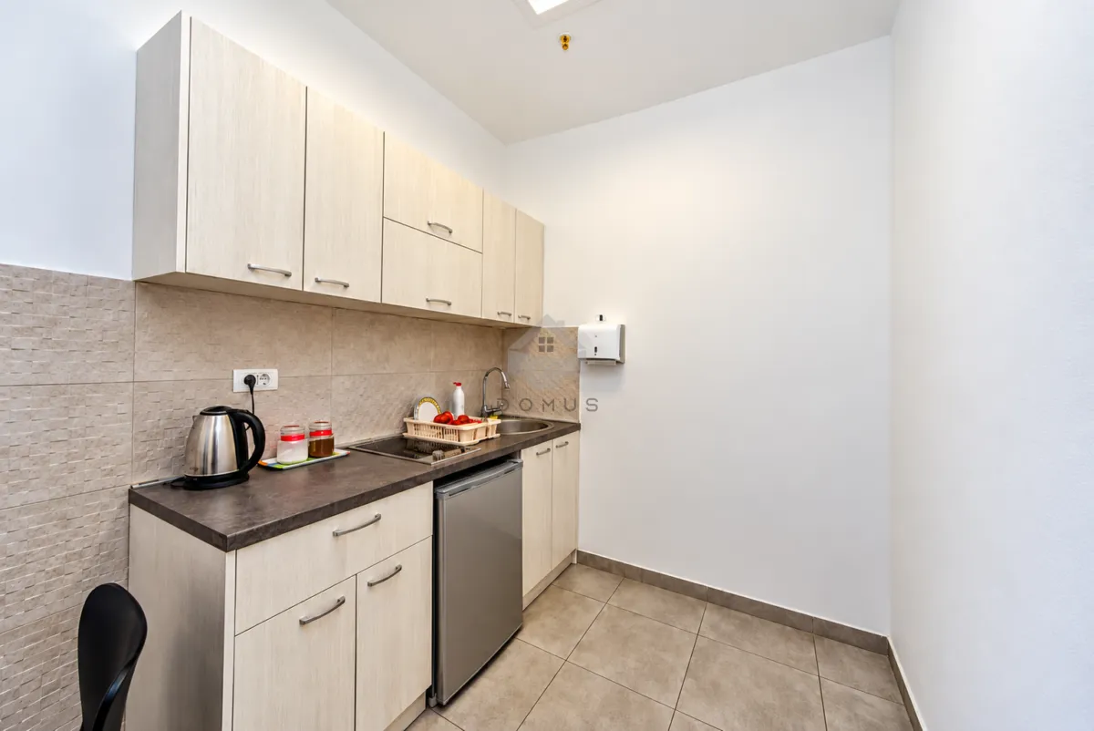 Small kitchenette with white cabinets and a built-in refrigerator.