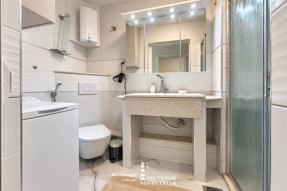 Svijetlo opremljeno kupatilo sa umivaonikom, WC šoljom i tuš kabinom.