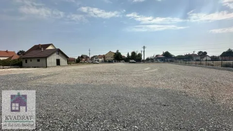 View of a spacious fenced plot with gravel and surrounding buildings. - image 7
