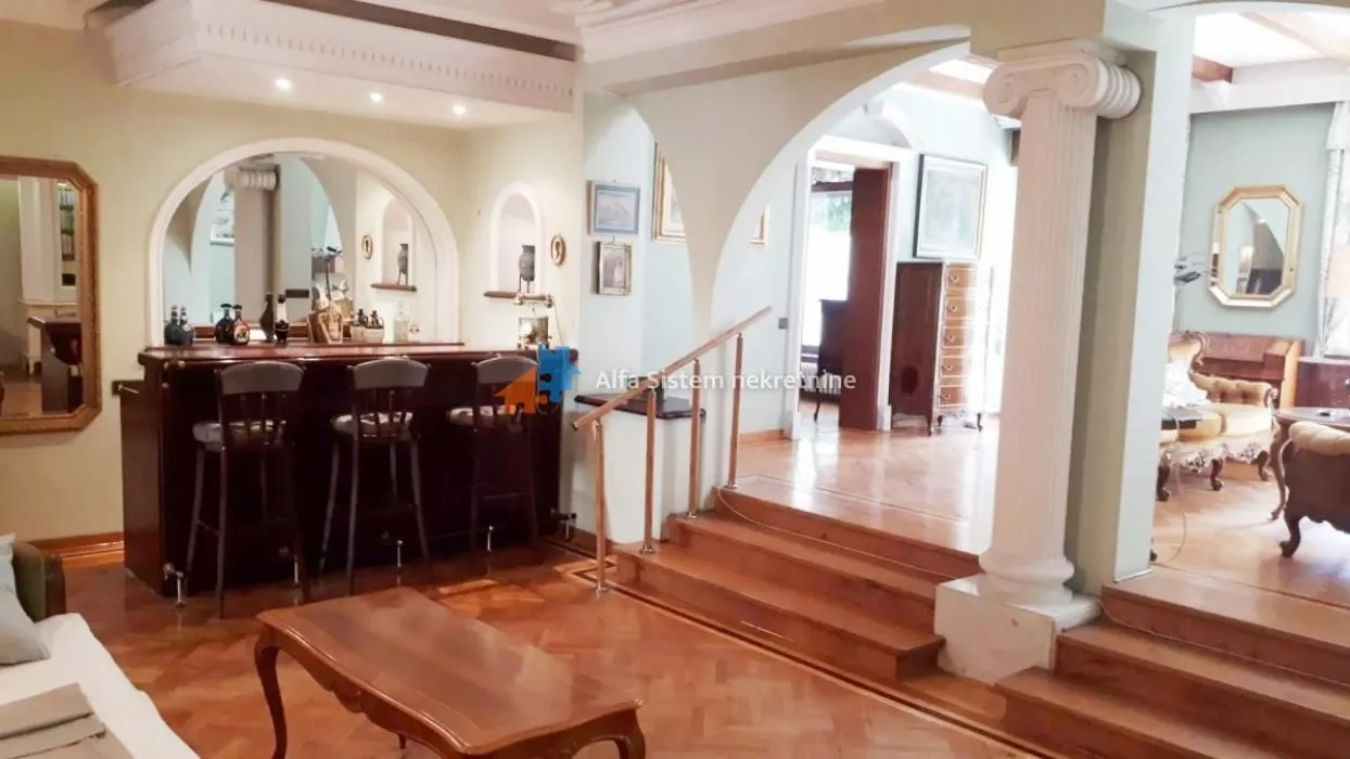 Living room with a bar counter and wooden stairs.