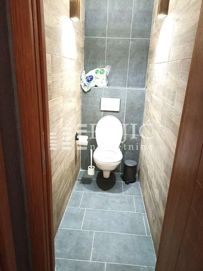 Small bathroom lined with ceramic tiles and a toilet.