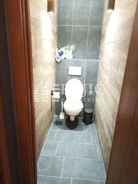 Small bathroom lined with ceramic tiles and a toilet. - image 11