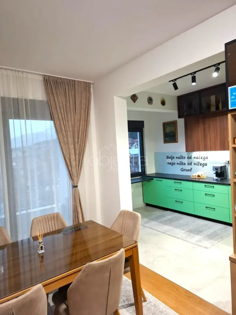 Trpezarija povezana sa kuhinjom u svijetlom enterijeru.