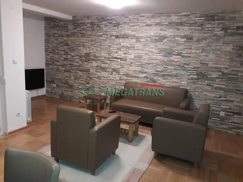 Living room with a sofa set and a decorative stone-clad wall.