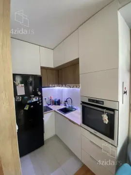 Small equipped kitchen with white cabinets and built-in appliances. - image 5