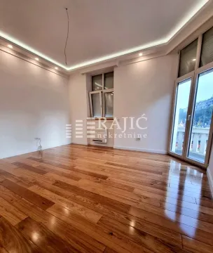 Empty room with wooden flooring and a drop ceiling with lighting. - image 3