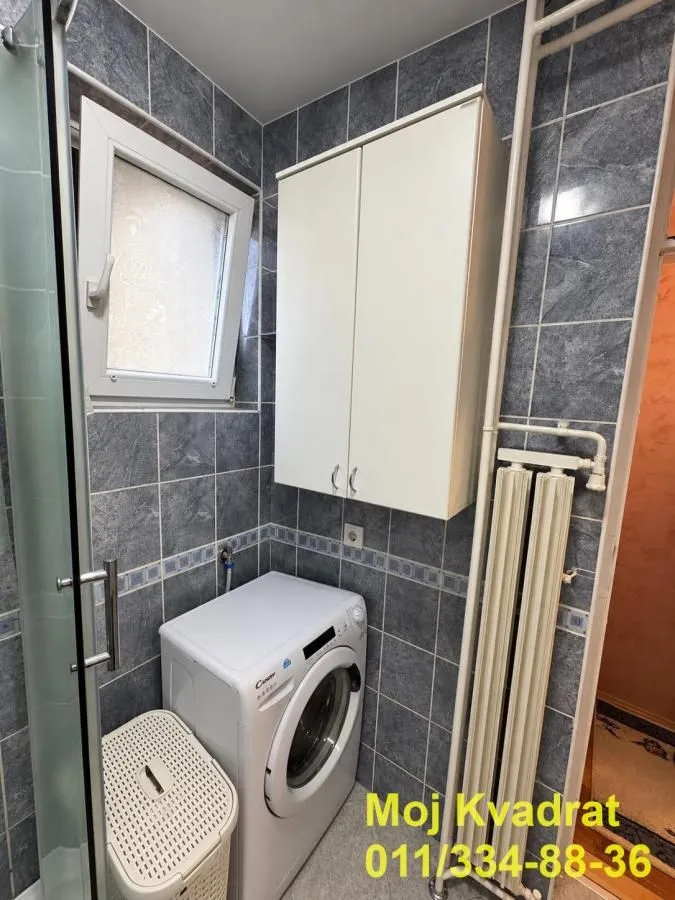 Bathroom with a washing machine, a wall cabinet and a window.