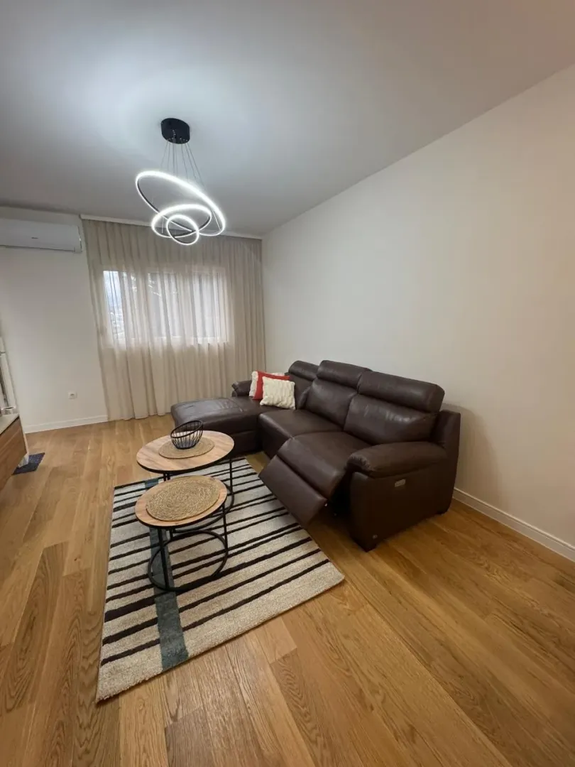 Living room with a brown sectional sofa, coffee table, and modern chandelier.