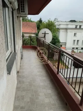 Dugi popločani balkon sa metalnom ogradom i pogledom na okolne zgrade. - image 2