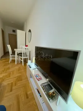 Living room with a TV and a dining area in the background. - image 3