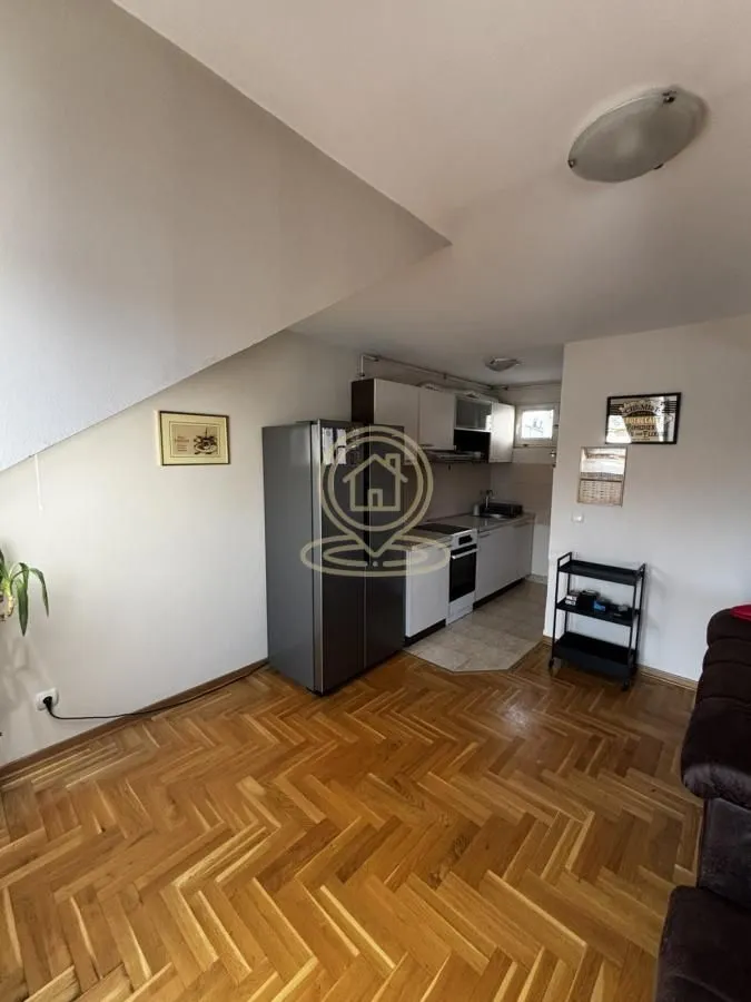 Small kitchen with a refrigerator and wooden parquet flooring.