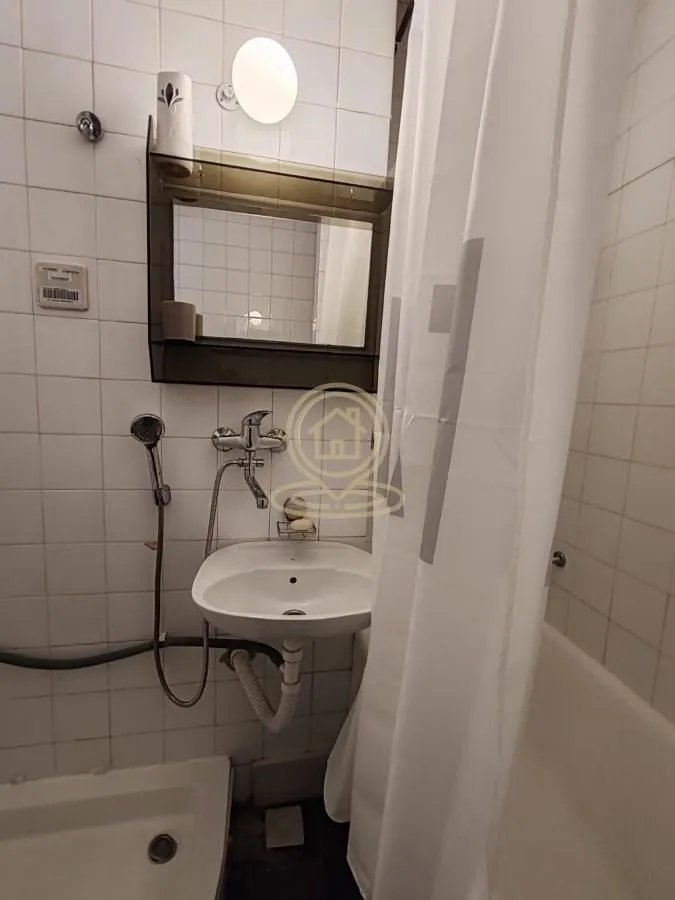Small bathroom with a sink, mirror, and bathtub.