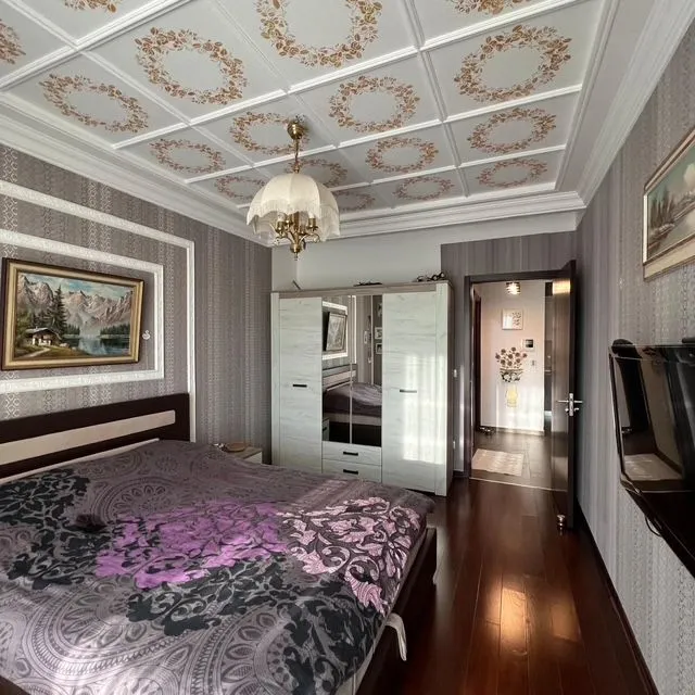 Furnished bedroom with a double bed, wardrobe, and decorative ceiling.