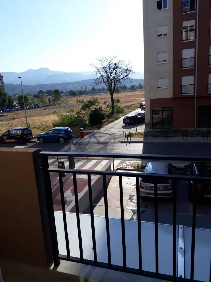 View from the balcony overlooking the street, parking lot, and surrounding mountains.