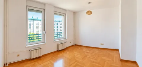 Empty bright room with hardwood flooring and two windows overlooking neighboring buildings. - image 5