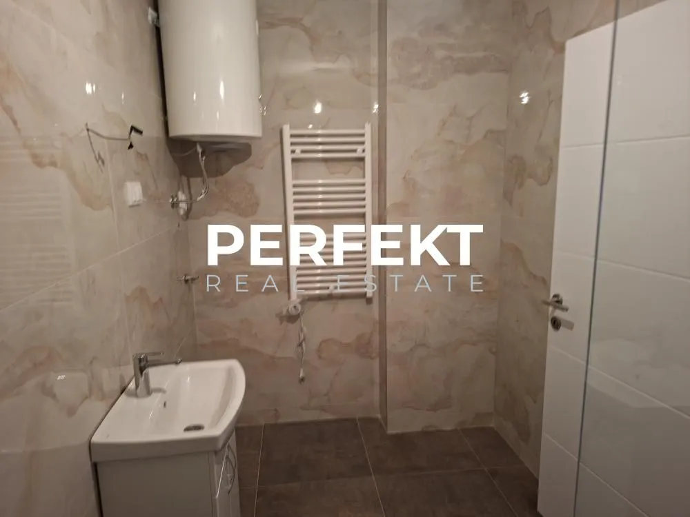 Manje kupatilo obloženo keramičkim pločicama sa umivaonikom i bojlerom.