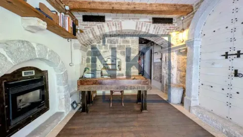 Rustic living room with stone walls, wooden beams, and a built-in fireplace. - image 4