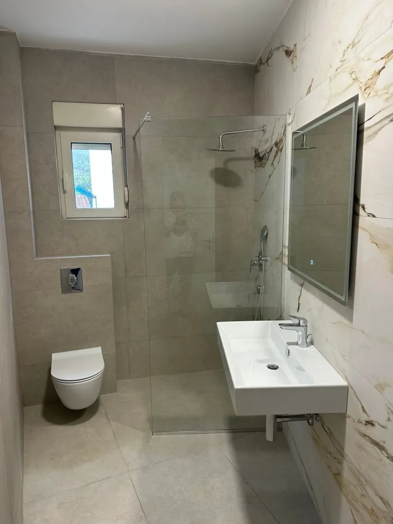 A modern bathroom equipped with a walk-in shower and a washbasin.