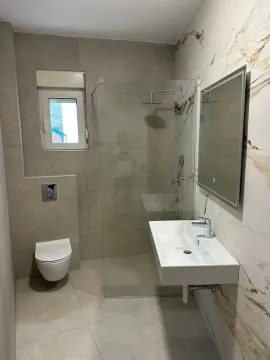 A modern bathroom equipped with a walk-in shower and a washbasin. - image 4