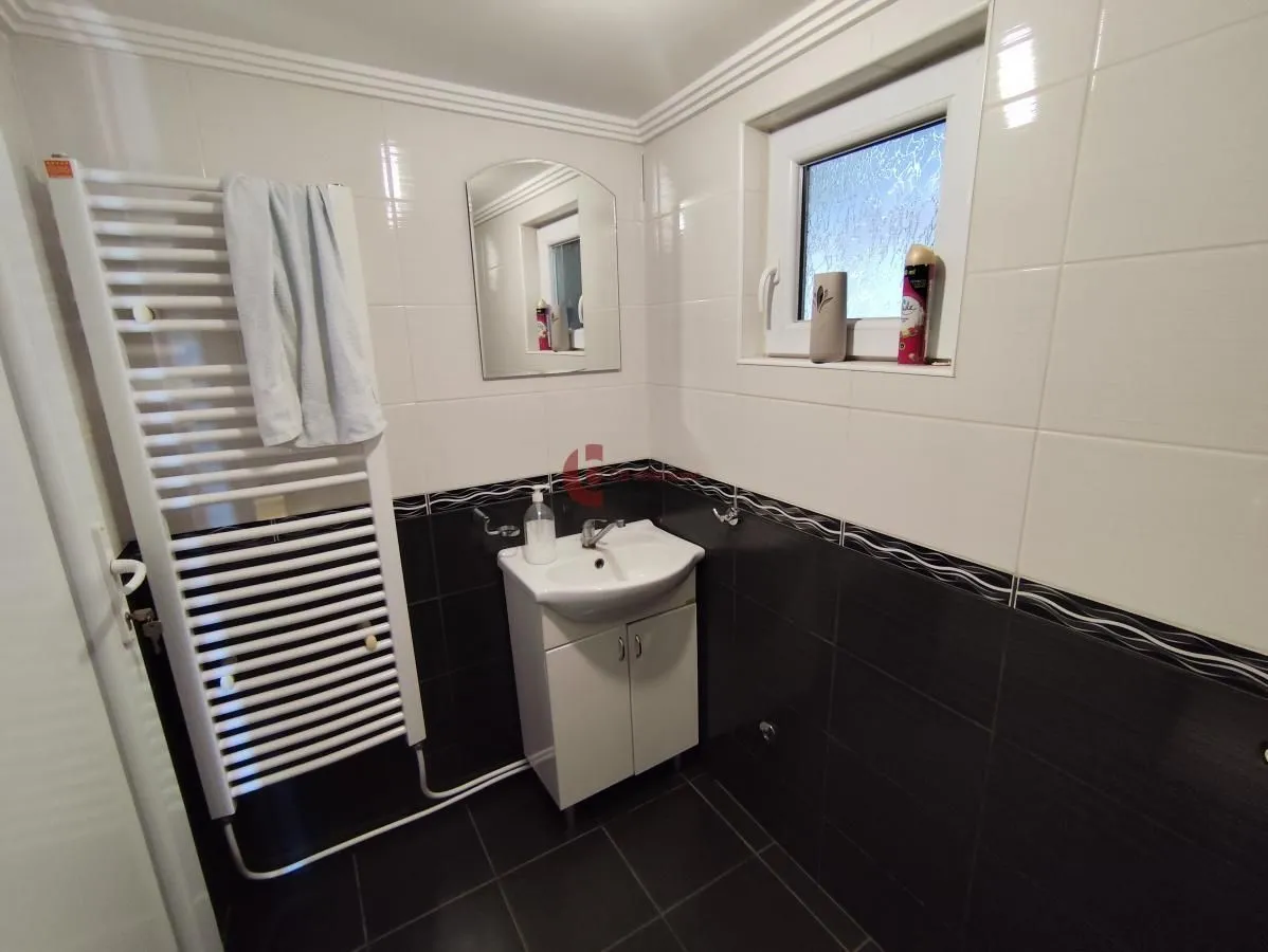 Bathroom with a sink, mirror, towel radiator, and a window.