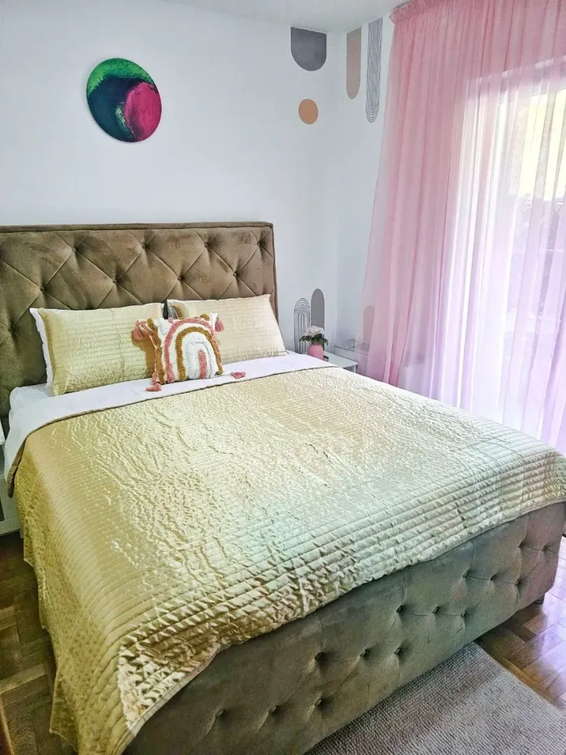 A decorated bedroom with a double bed and pink curtains.
