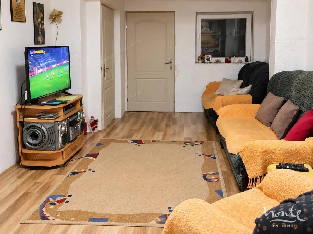 Living room with sofa set, television, and dining table in the background.