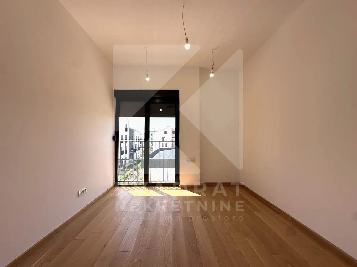 Empty room with wooden flooring and access to the terrace.