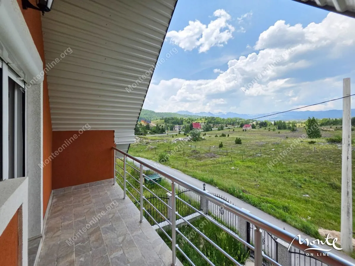 Natkriveni balkon sa metalnom ogradom i pogledom na prirodu i okolinu.