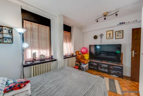 Bedroom with a bed, large TV and two windows. - image 11