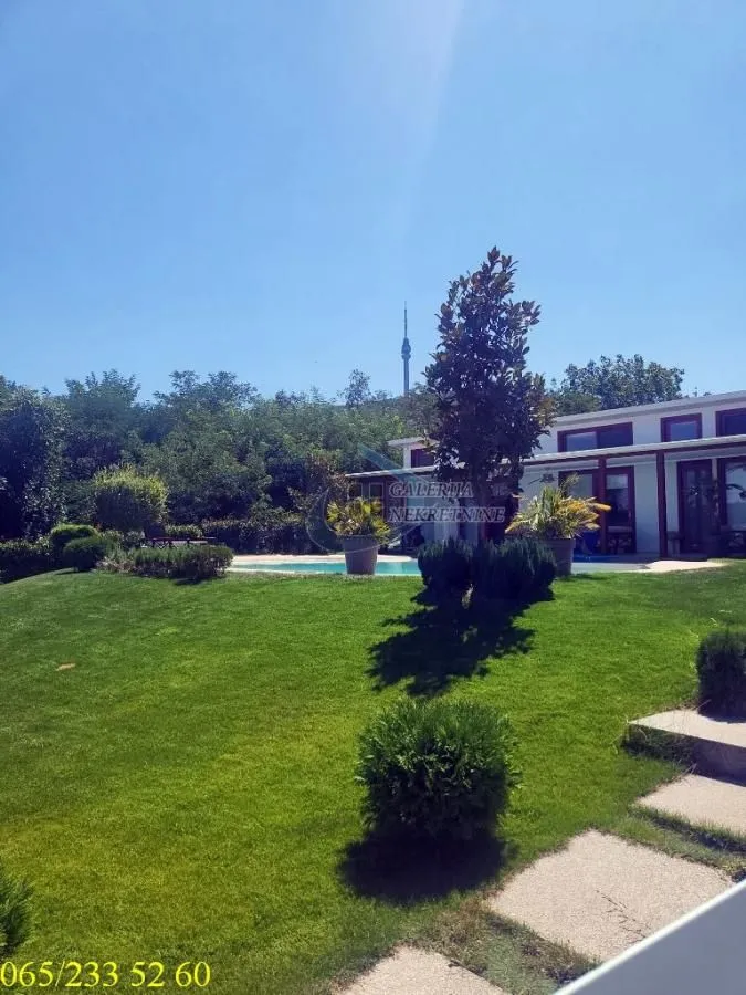 Pogled na dvorište sa bazenom i travnjakom ispred kuće.