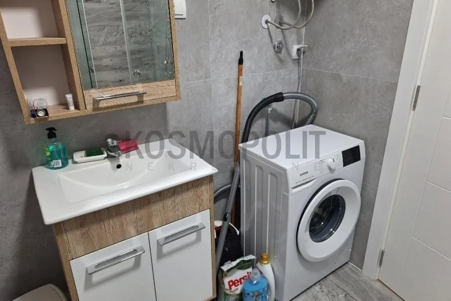Kupatilo sa umivaonikom, ormarićem, ogledalom i veš mašinom.